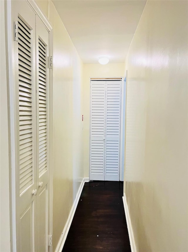 hallway with dark wood-style floors and baseboards