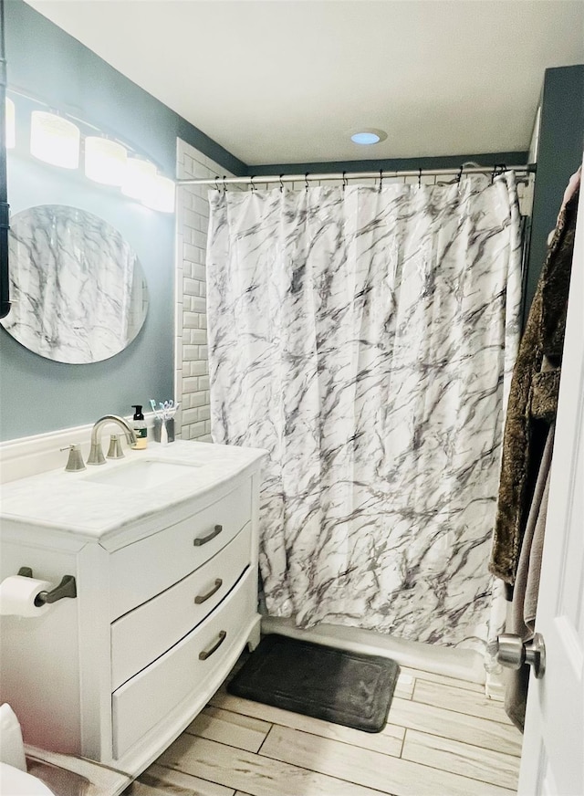 full bath featuring wood finish floors, vanity, and shower / bath combo