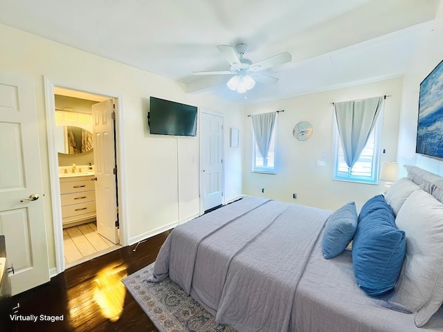 bedroom with ensuite bathroom, a sink, a ceiling fan, baseboards, and dark wood finished floors