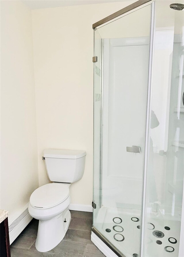 bathroom with a baseboard heating unit, a stall shower, wood finished floors, and toilet