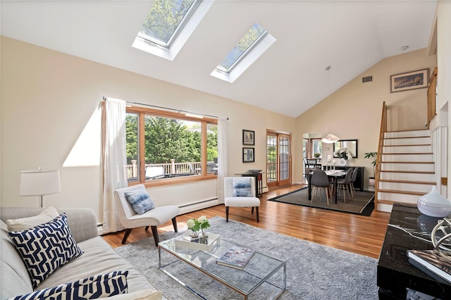 living area featuring a skylight, baseboard heating, high vaulted ceiling, and plenty of natural light