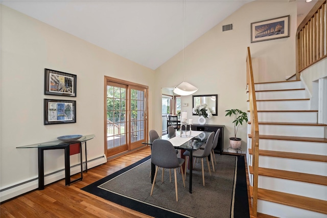 dining area featuring wood finished floors, high vaulted ceiling, visible vents, stairway, and a baseboard radiator