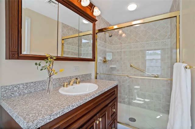 full bathroom featuring vanity, a shower stall, and visible vents