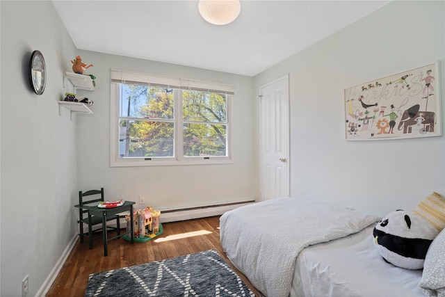 bedroom with wood finished floors, baseboards, and a baseboard heating unit