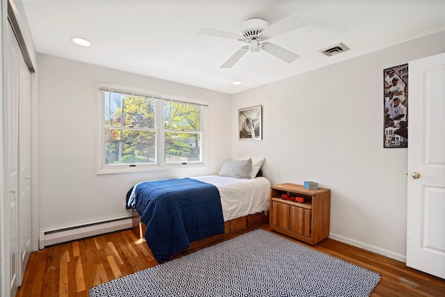 bedroom featuring baseboard heating, baseboards, ceiling fan, visible vents, and wood finished floors