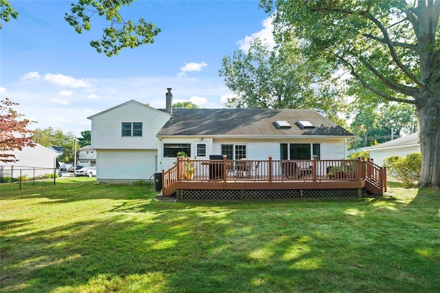 back of house featuring a yard, a chimney, a wooden deck, and fence