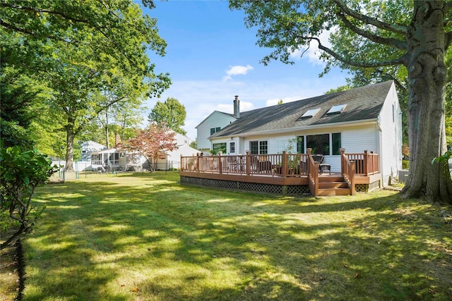 rear view of property featuring a yard, roof with shingles, a wooden deck, and a fenced backyard