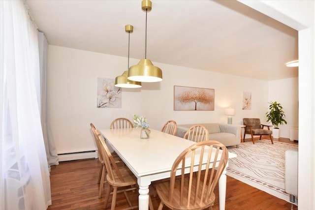 dining area featuring a baseboard heating unit and wood finished floors