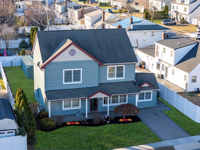 view of front of home with roof with shingles, a front yard, a fenced backyard, and a residential view