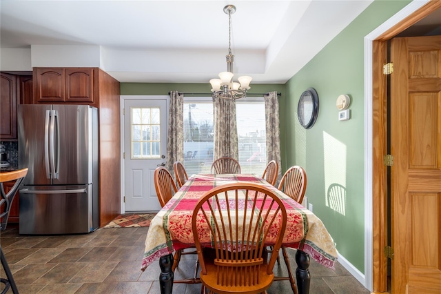 dining area featuring a chandelier, stone finish flooring, and baseboards