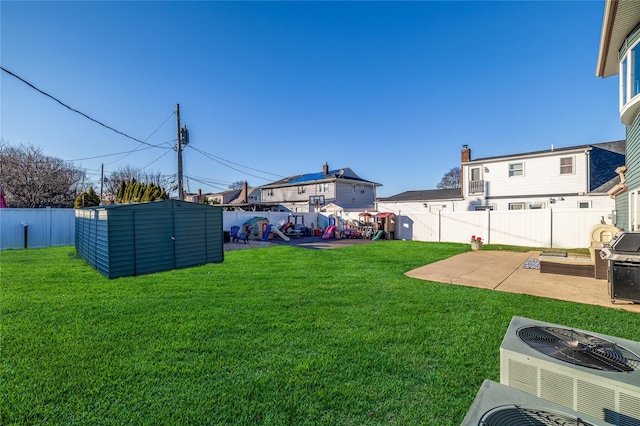 view of yard with an outbuilding, a storage shed, a patio area, cooling unit, and a fenced backyard