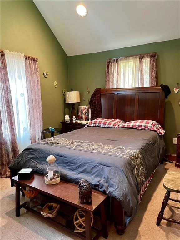 bedroom with light carpet and lofted ceiling