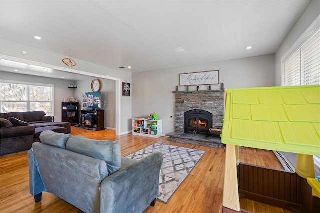 living room featuring a stone fireplace and wood-type flooring