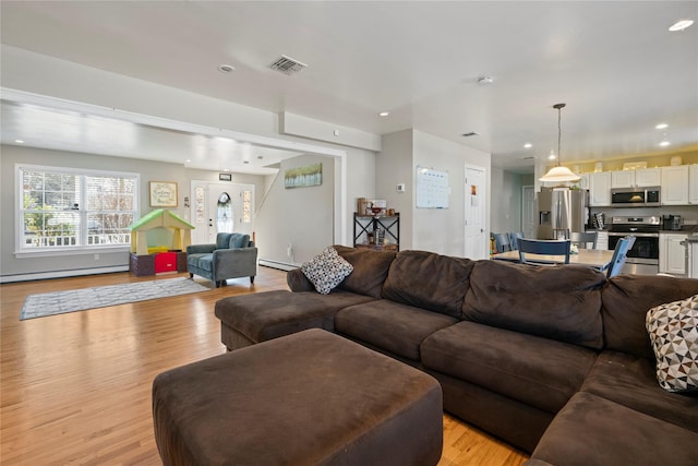 living room featuring a baseboard heating unit and light hardwood / wood-style flooring