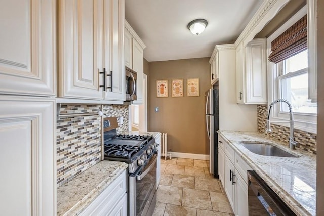 kitchen with white cabinetry, stainless steel appliances, sink, light stone counters, and decorative backsplash