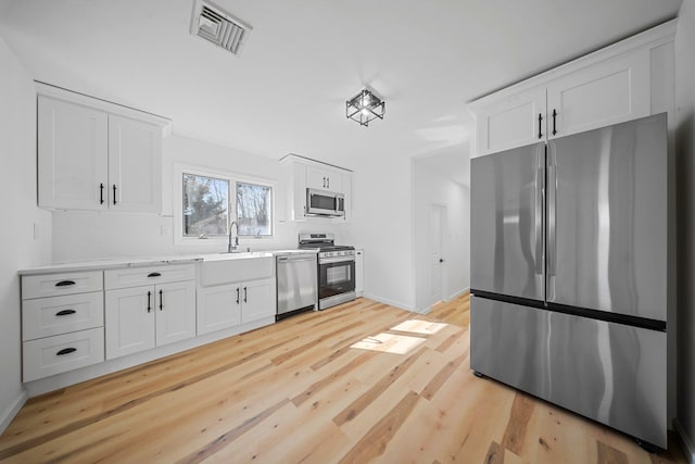 kitchen featuring white cabinets, light hardwood / wood-style floors, and appliances with stainless steel finishes