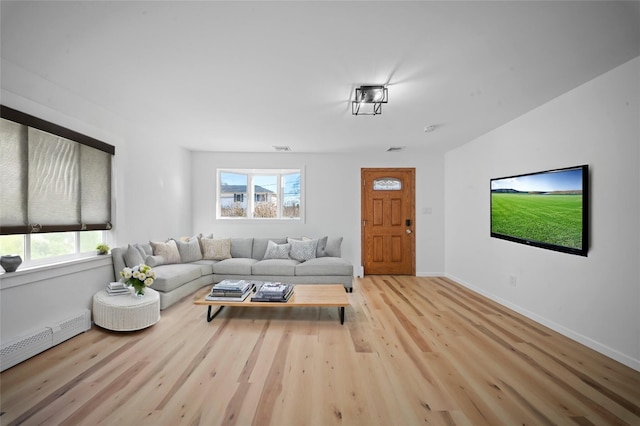 living room with baseboard heating and light hardwood / wood-style floors