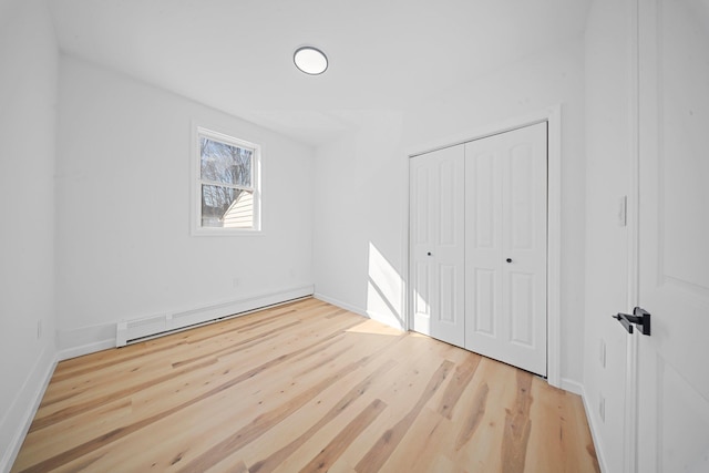 unfurnished bedroom with light hardwood / wood-style flooring, a closet, and a baseboard radiator