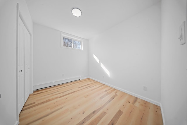 empty room featuring a baseboard radiator and hardwood / wood-style floors