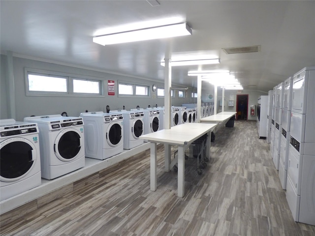 laundry area with hardwood / wood-style flooring, ornamental molding, washer and dryer, and stacked washer / drying machine