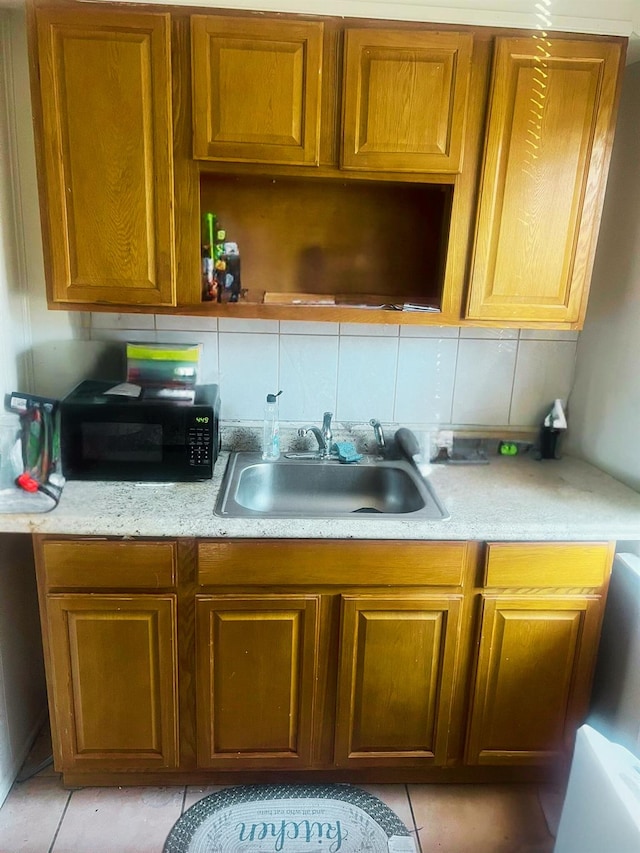 kitchen with light tile patterned flooring, sink, and tasteful backsplash