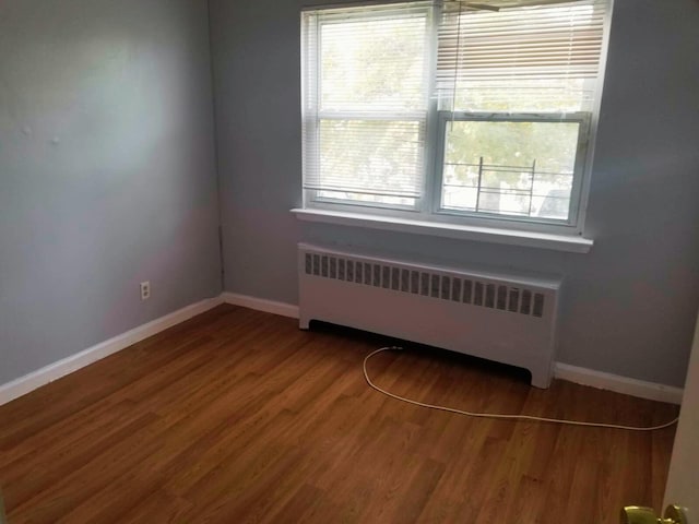 empty room featuring radiator and wood-type flooring