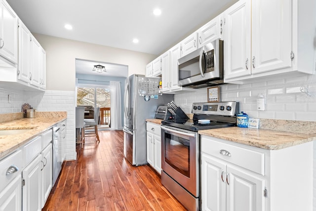 kitchen featuring stainless steel appliances, wood finished floors, and white cabinetry