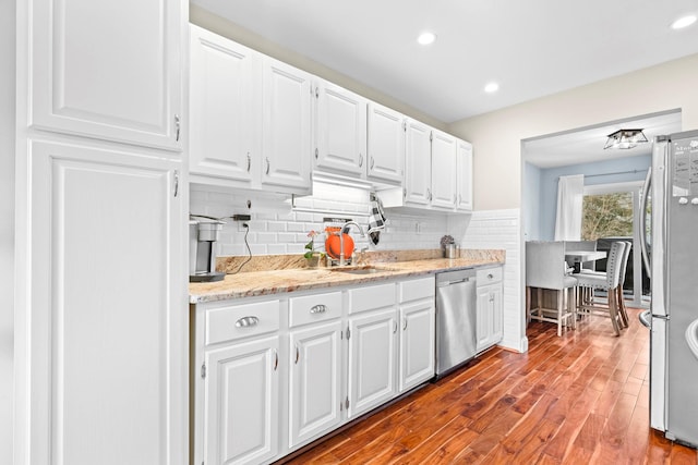 kitchen featuring light stone counters, white cabinetry, light wood-style floors, appliances with stainless steel finishes, and backsplash