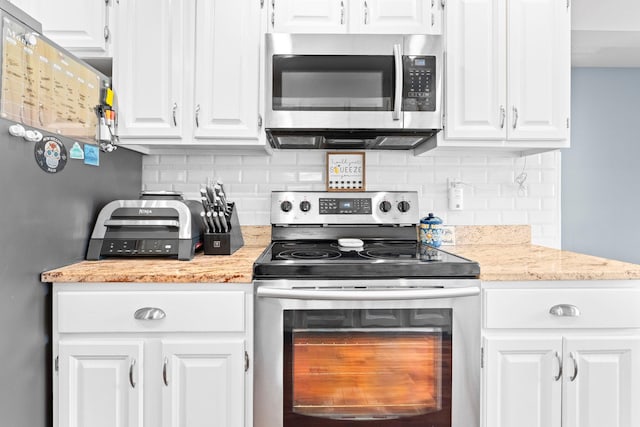 kitchen with tasteful backsplash, white cabinetry, stainless steel appliances, and light stone counters