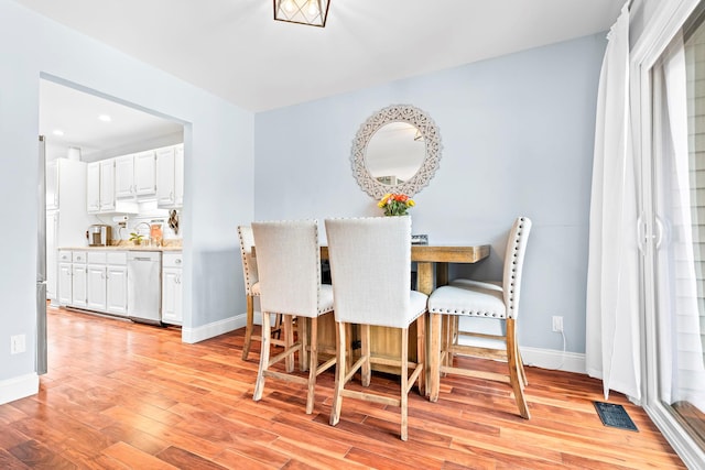 dining room featuring baseboards, visible vents, and light wood-style floors