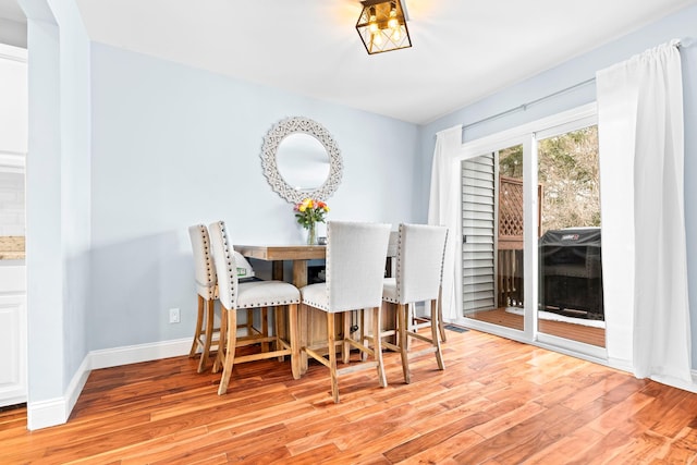 dining space featuring light wood-style flooring and baseboards