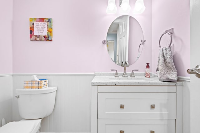 bathroom featuring toilet, vanity, and wainscoting