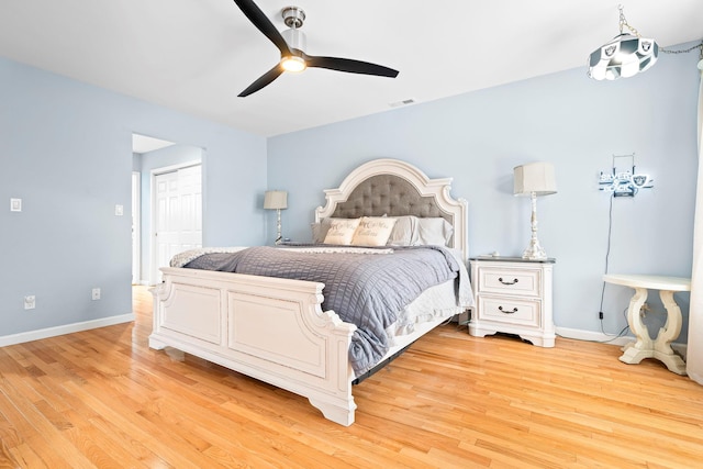 bedroom with light wood finished floors, a ceiling fan, visible vents, and baseboards