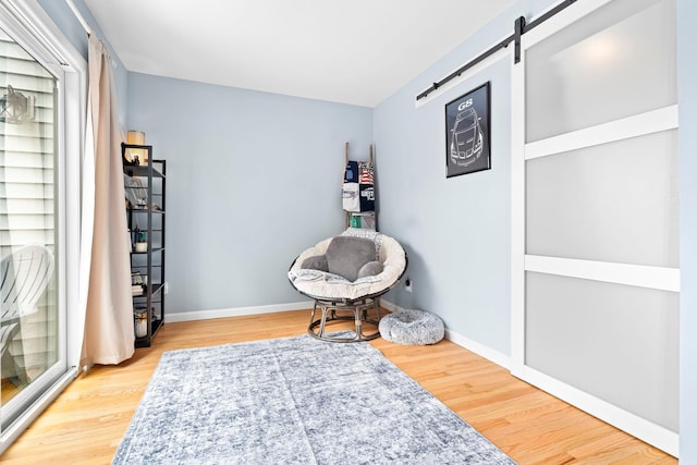 living area featuring baseboards, a barn door, and light wood-style floors