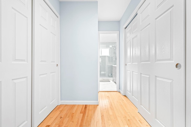 hallway with light wood-type flooring and baseboards