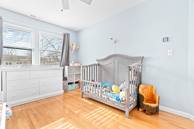 bedroom with light wood-style floors, ceiling fan, visible vents, and baseboards