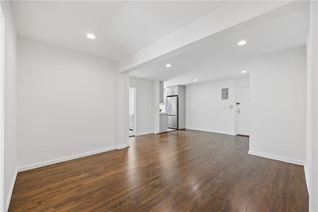 unfurnished living room with recessed lighting, electric panel, dark wood finished floors, and baseboards