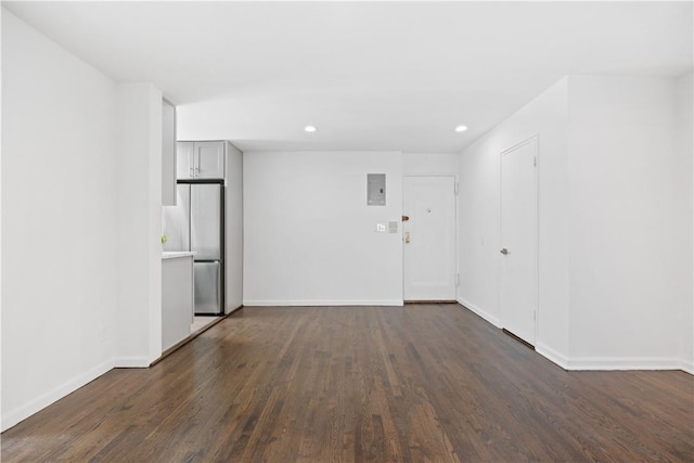 spare room with recessed lighting, electric panel, dark wood finished floors, and baseboards