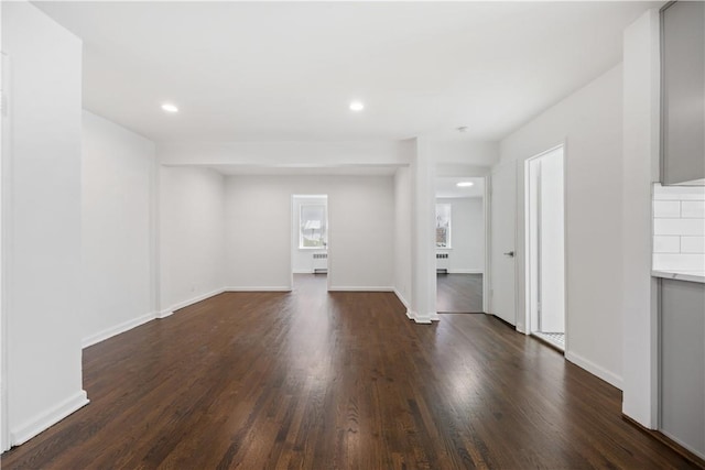 unfurnished living room featuring dark wood-style floors, recessed lighting, radiator heating unit, and baseboards