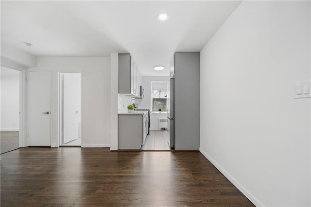 unfurnished living room featuring recessed lighting, radiator, baseboards, and wood finished floors