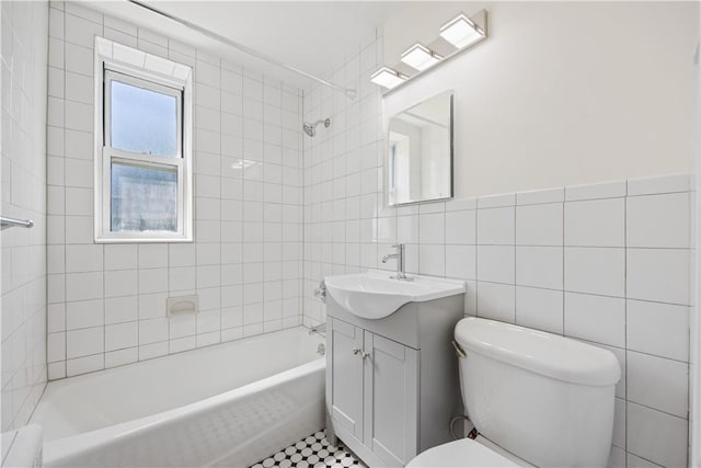 bathroom with washtub / shower combination, tile walls, toilet, and vanity