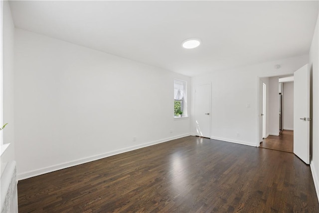 empty room featuring dark wood finished floors and baseboards