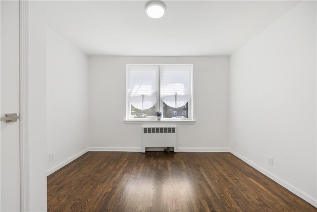 spare room featuring baseboards, radiator heating unit, and wood finished floors