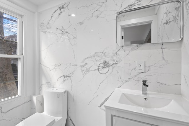 bathroom with toilet, stone wall, and vanity