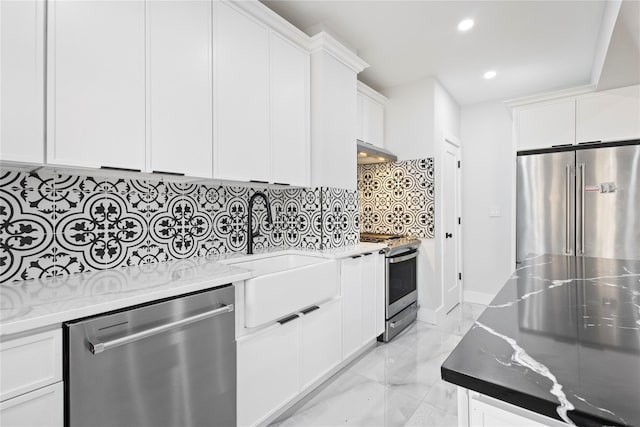 kitchen with light stone counters, under cabinet range hood, marble finish floor, appliances with stainless steel finishes, and tasteful backsplash