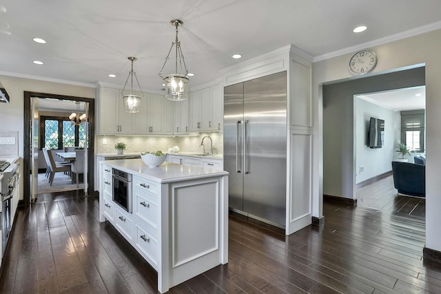 kitchen featuring an inviting chandelier, a sink, light countertops, backsplash, and stainless steel built in refrigerator