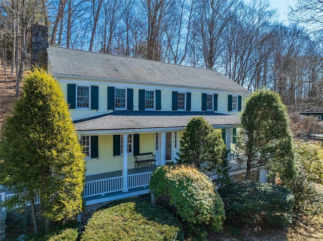 view of front of property featuring covered porch, a shingled roof, and a chimney