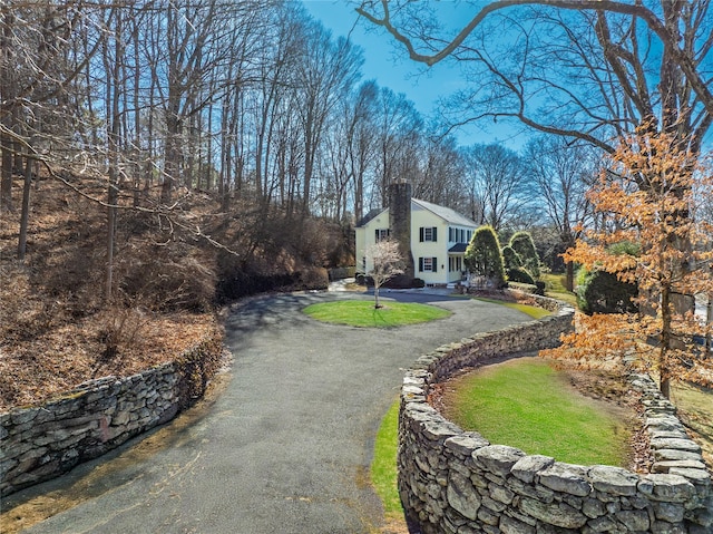 exterior space with aphalt driveway and a chimney