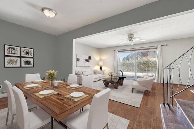 dining room with ceiling fan, stairs, and dark wood-style flooring