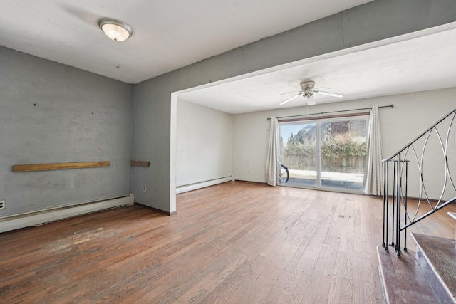 unfurnished room featuring a baseboard radiator, ceiling fan, stairway, wood finished floors, and a baseboard heating unit